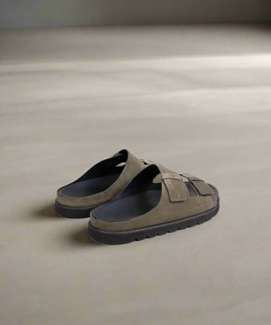 Brown sandals with black soles on a gray background