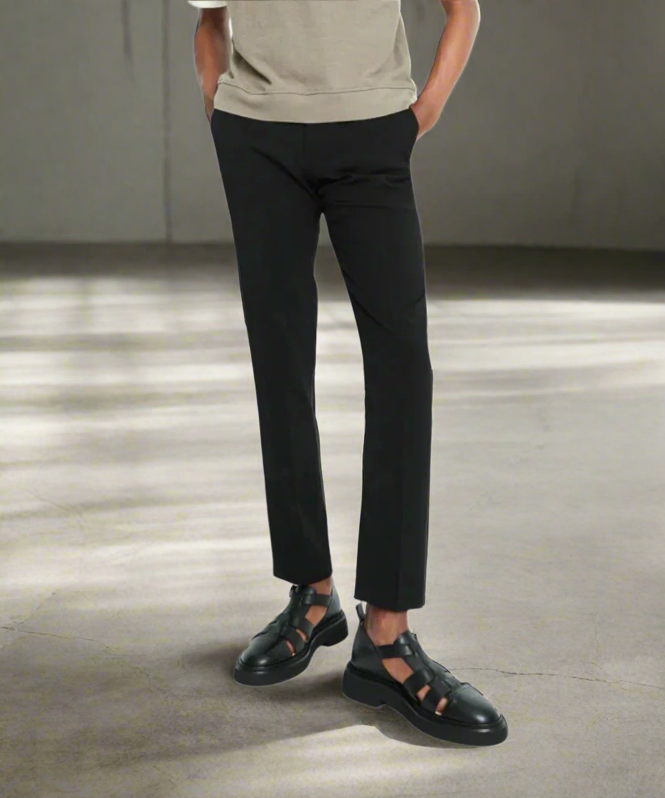 Person wearing black pants and black shoes on a gray background