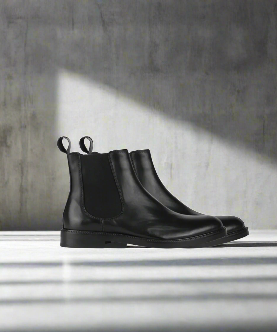 Black Chelsea boots on a light gray background