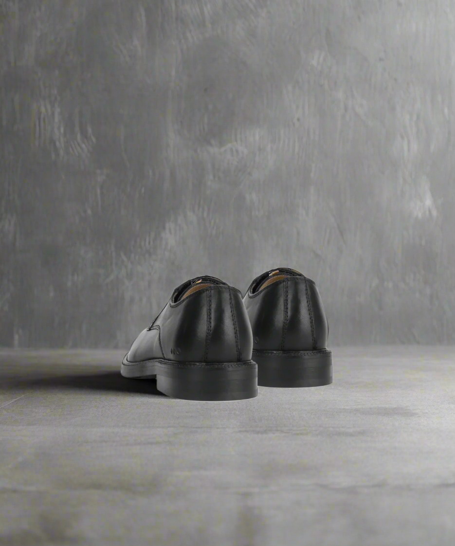 Black leather shoes on a gray background