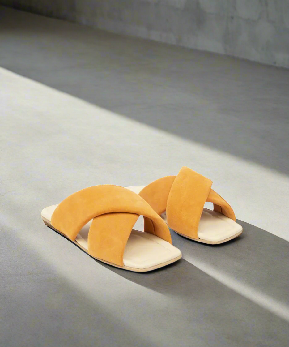 Pair of mustard yellow sandals on a gray background