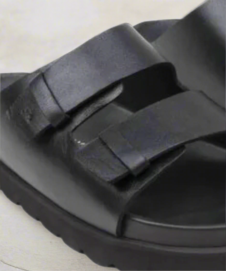 Black sandal with multiple straps on a gray background