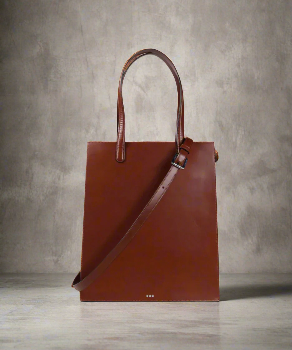 Brown leather tote bag on a gray background