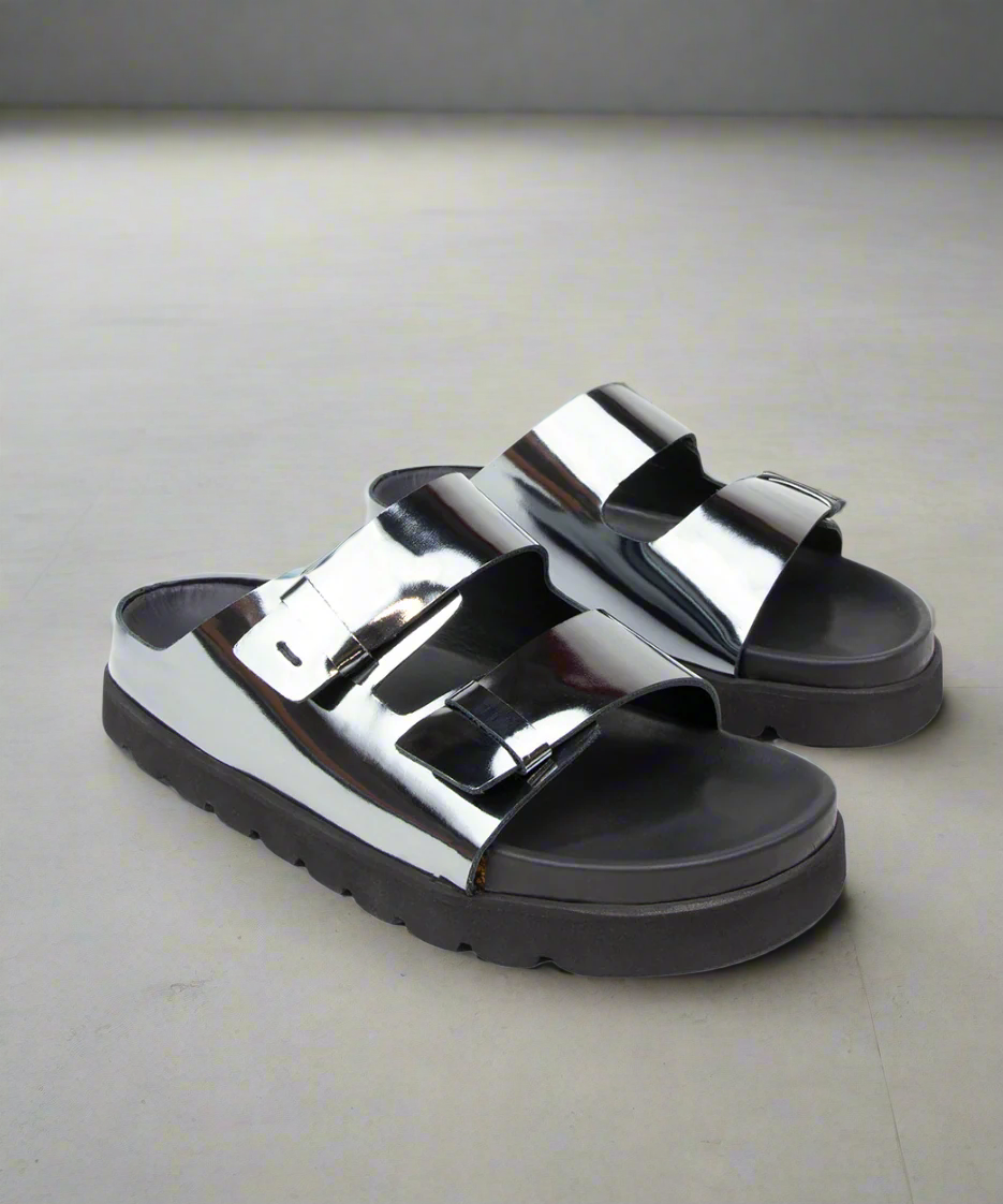 Pair of silver and black platform sandals on a gray background