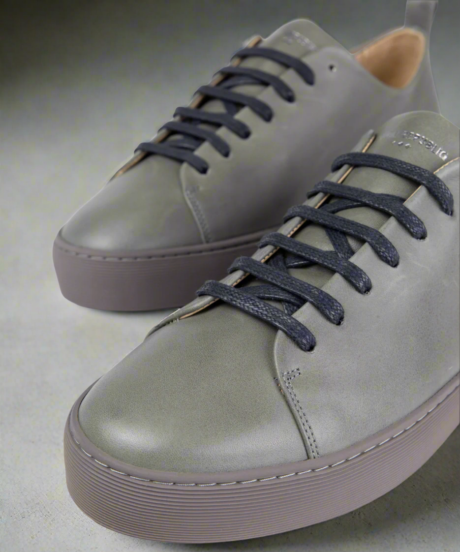 Gray sneakers with navy laces on a gray background