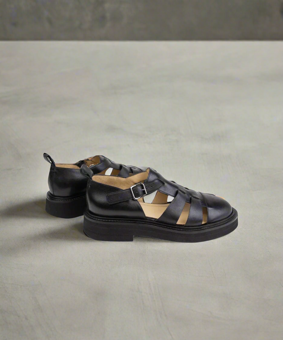 Black leather sandals on a gray background