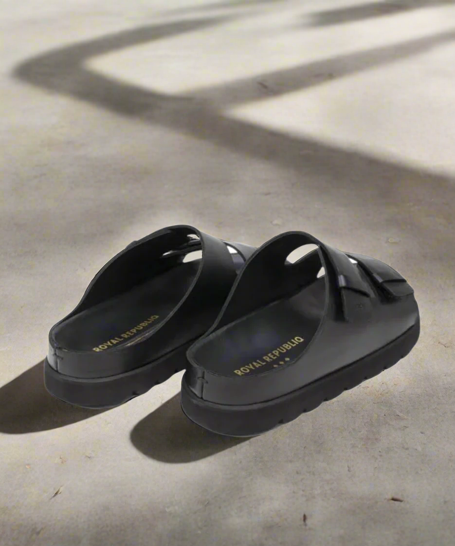 Black sandals with 'Royal RepubliQ' branding on a gray background