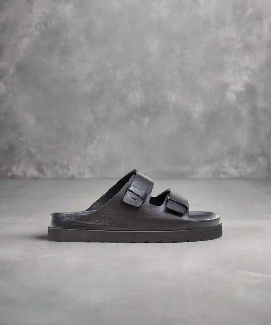 Black sandal with a thick sole on a gray background