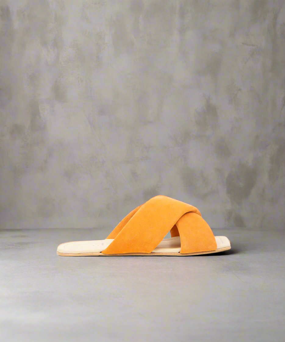 Orange sandal with a criss-cross strap design on a gray background