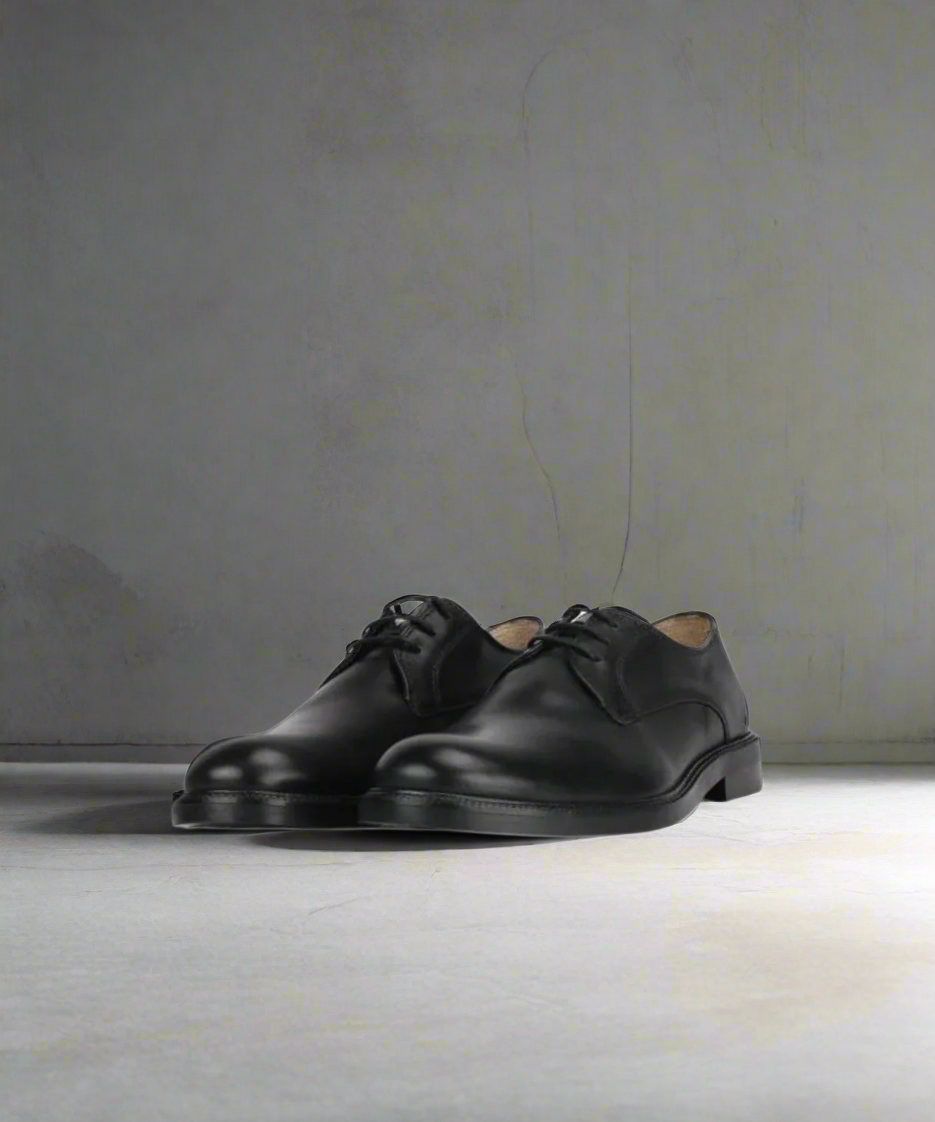 Pair of black leather shoes on a gray background