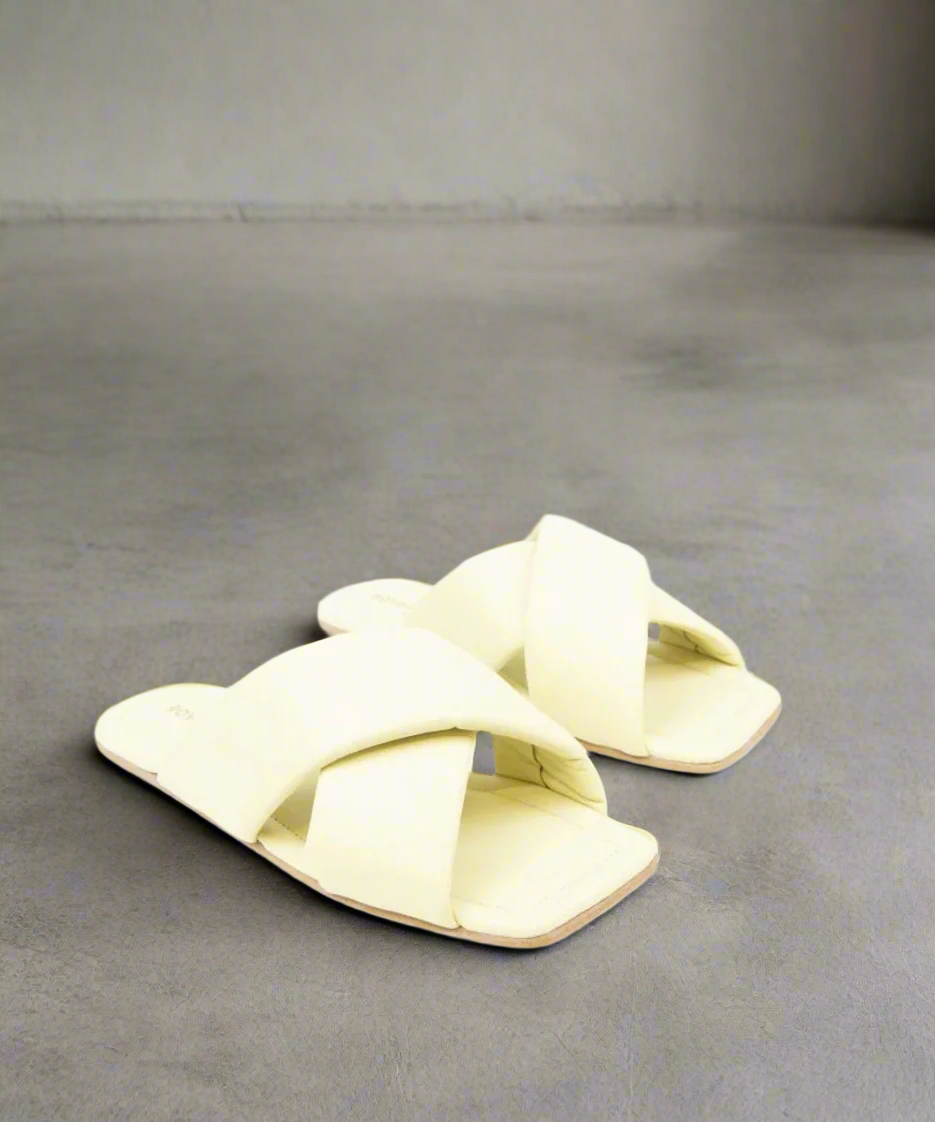Pair of light yellow sandals with a bow design on a grey background