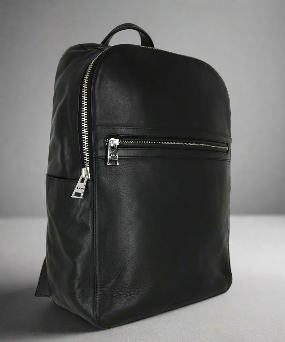 Black leather backpack with a zipper on a gray background
