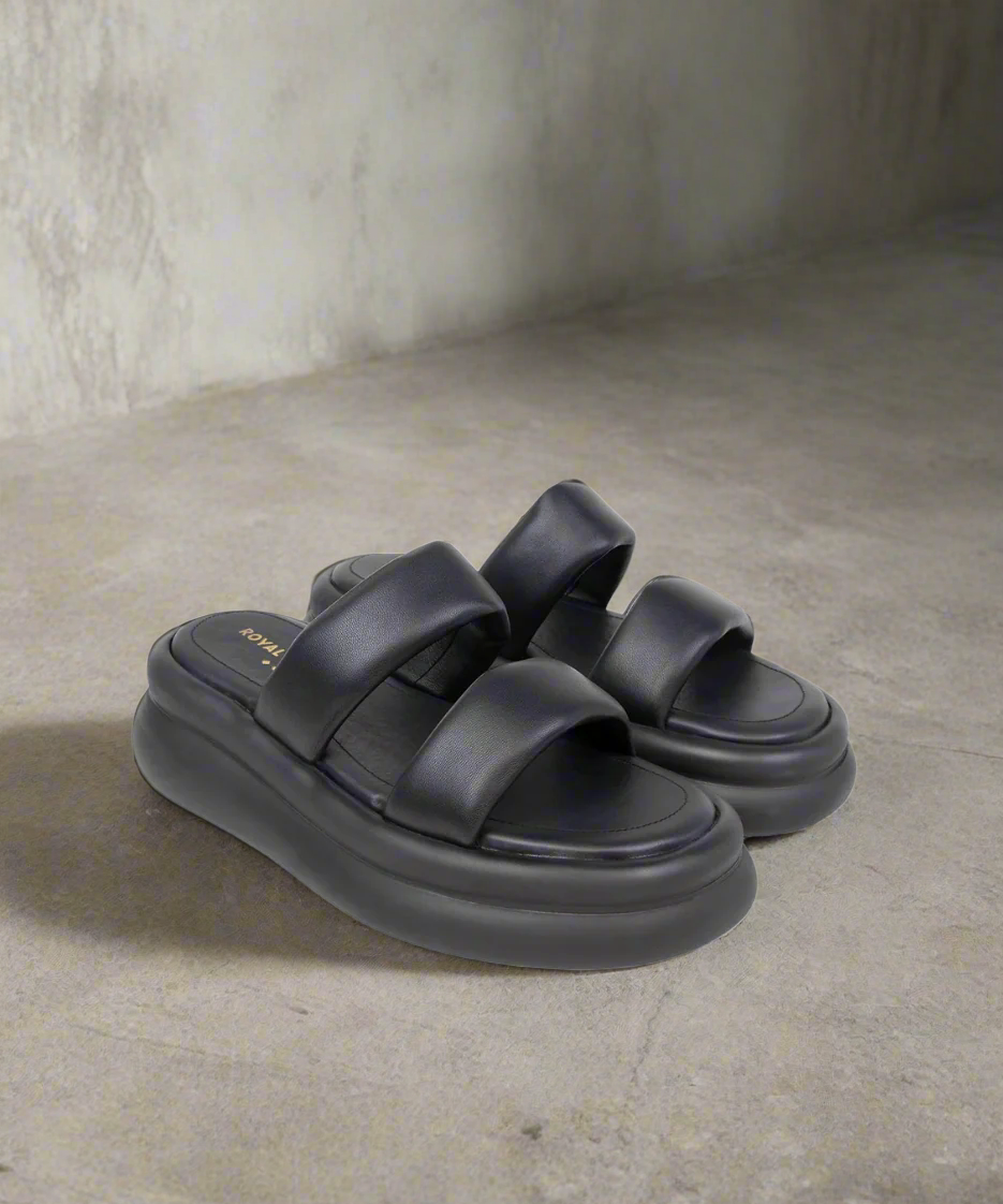 Black sandals with thick sole on a gray background