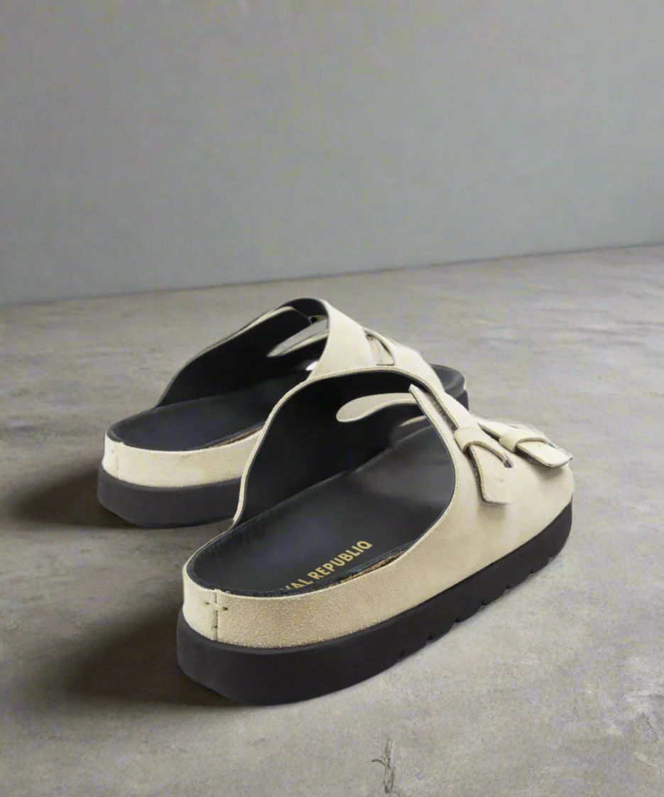 Pair of black and beige sandals on a gray background