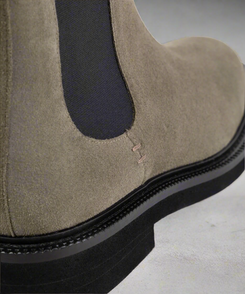 Close-up of a brown suede boot with a black sole on a black background