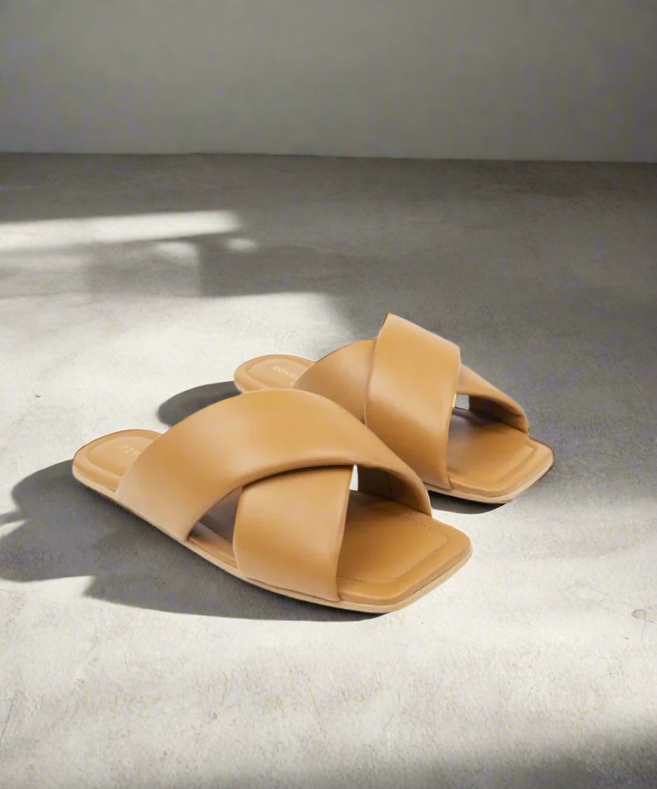 Pair of tan sandals with交叉straps on a grey background