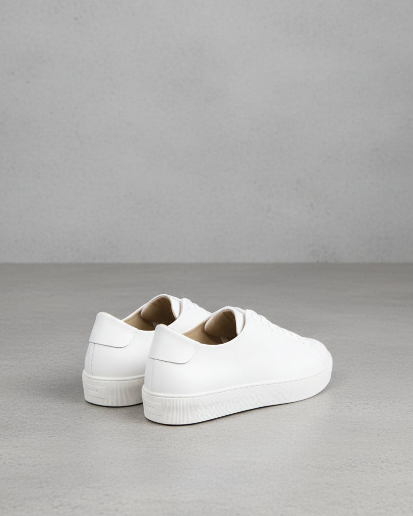 A single white Doric bound accent sneaker against a white background, showing the side profile of the shoe with visible lace eyelets and a heel counter.