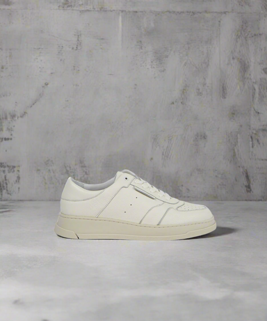 White Royal RepubliQ sneaker on a gray surface with a textured gray background