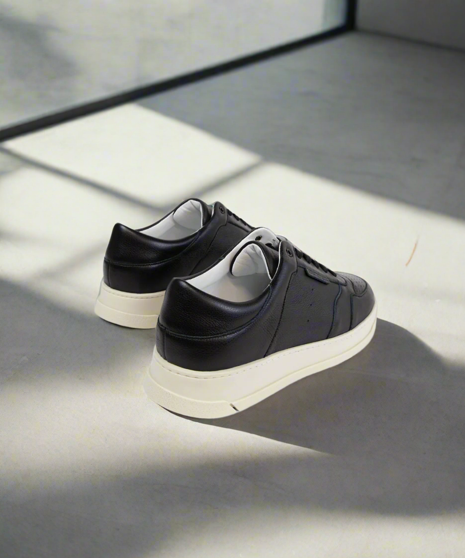 Black Royal RepubliQ sneakers with white soles on a reflective surface