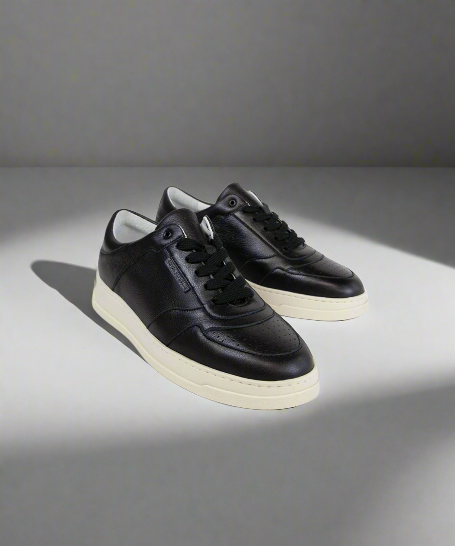 Black Royal RepubliQ sneakers with white soles on a gray background