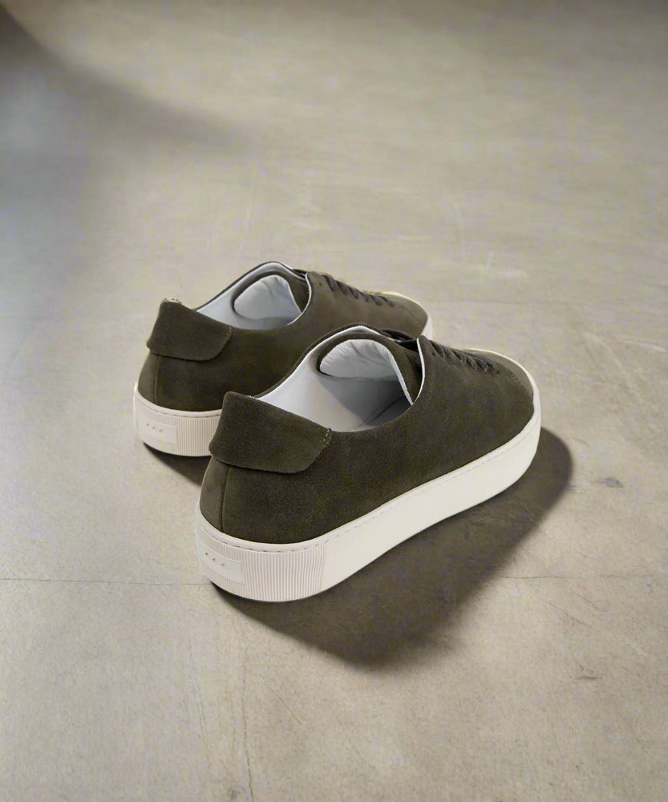 Pair of khaki suede shoes with velcro straps on a light gray background