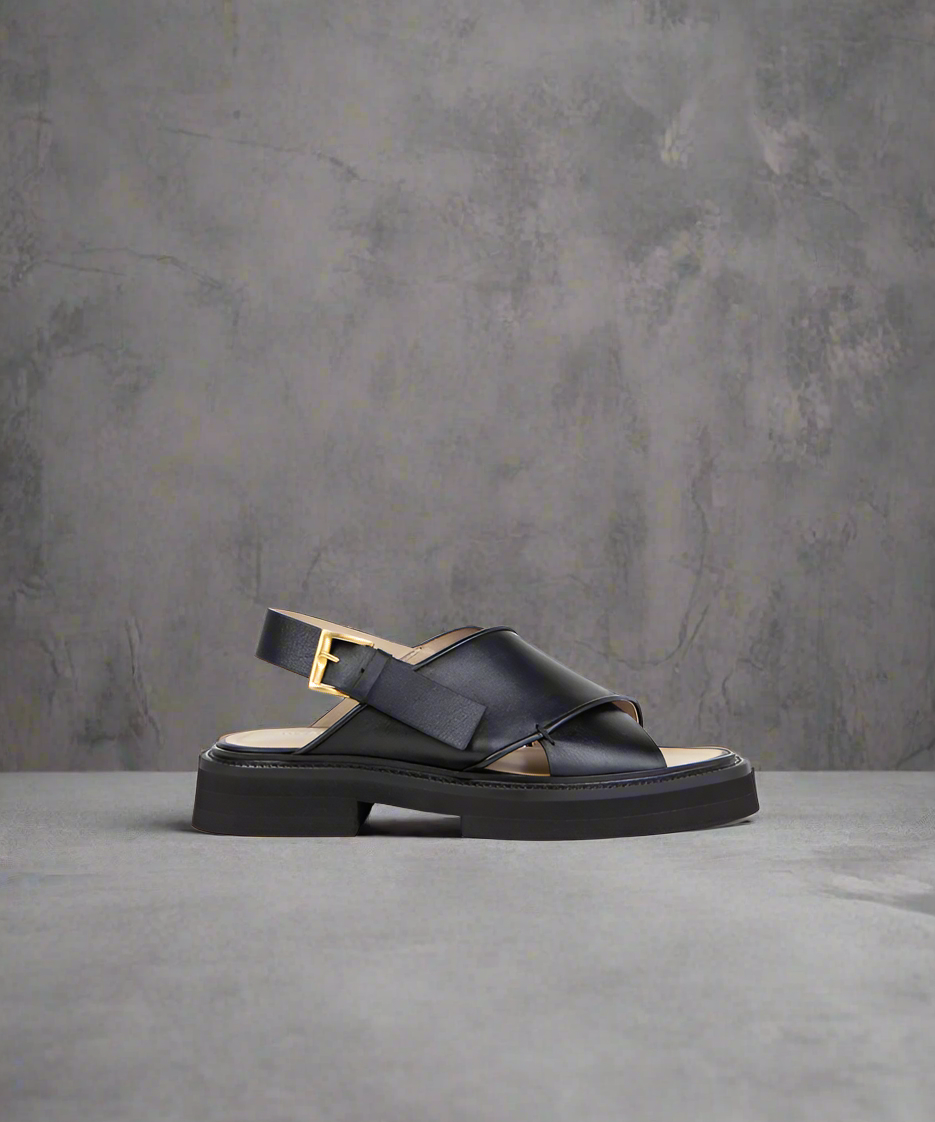 A black Jinx Blox sandal with a peep toe and thick strap, featuring intricate piping details.