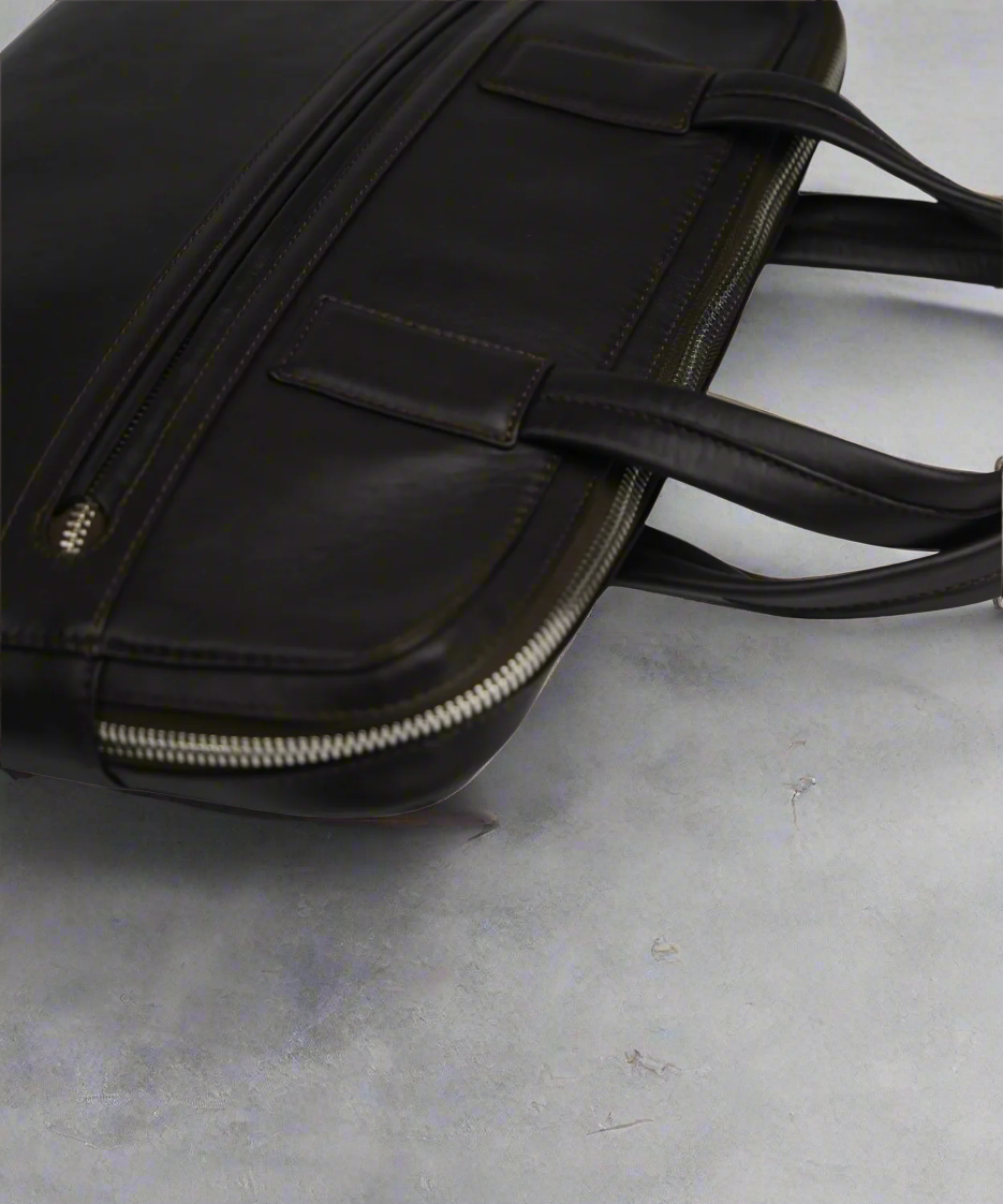 Slim Brown Royal RepubliQ leather briefcase on a gray surface