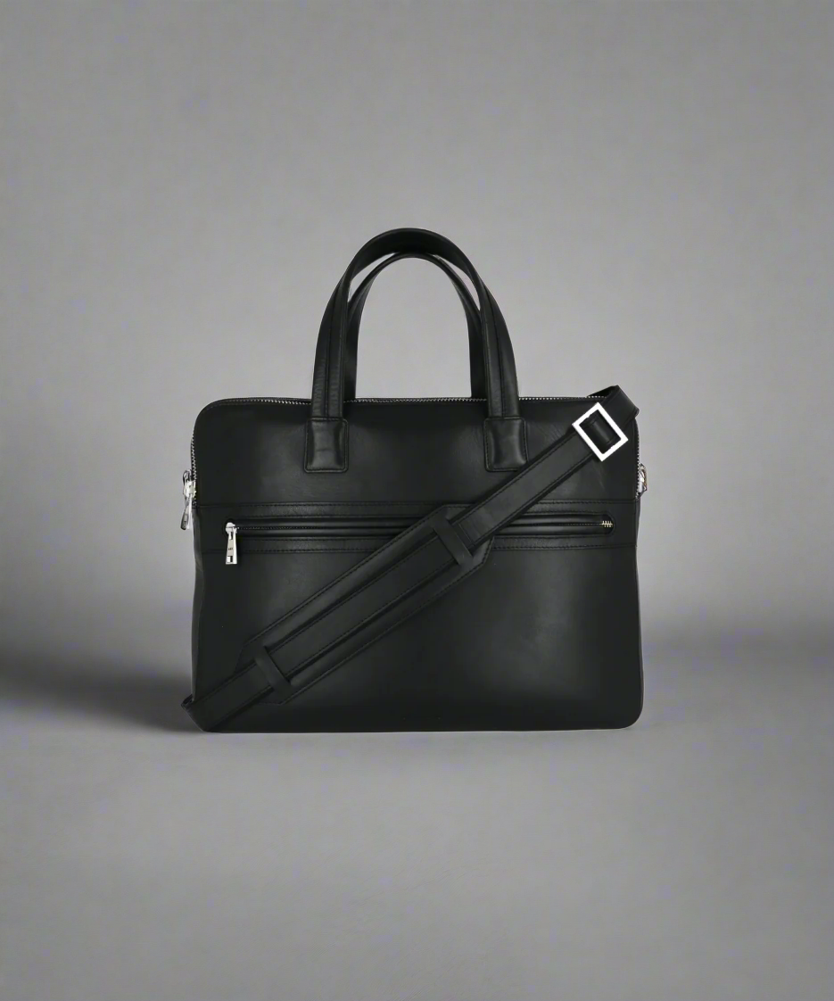 Black leather briefcase with shoulder strap on a gray background