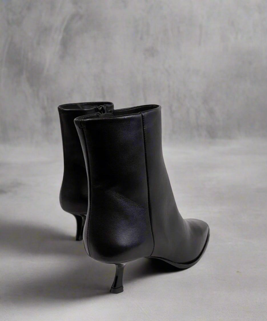Pair of black ankle boots on a gray background