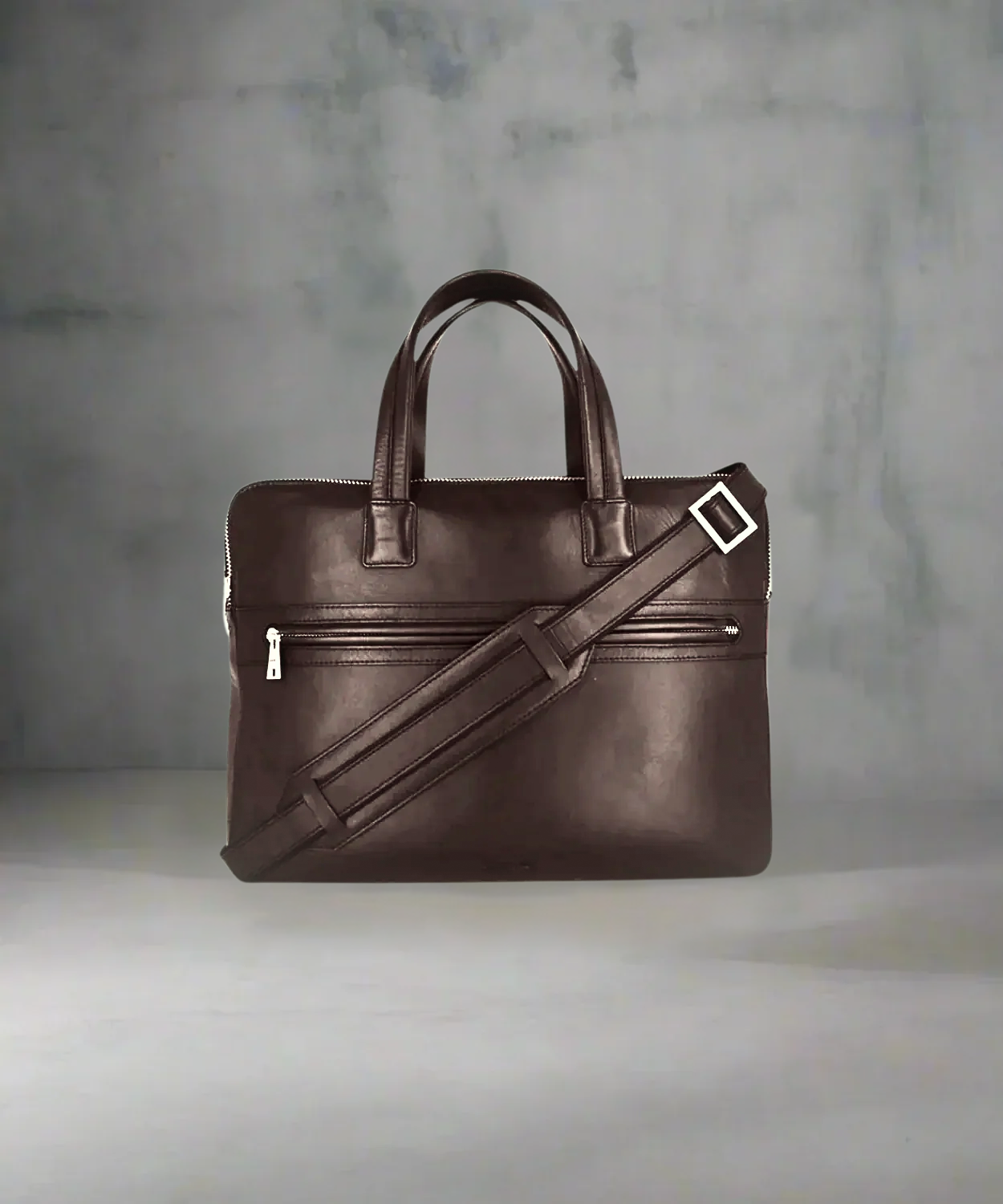 Brown Royal RepubliQ leather briefcase with a strap on a gray background