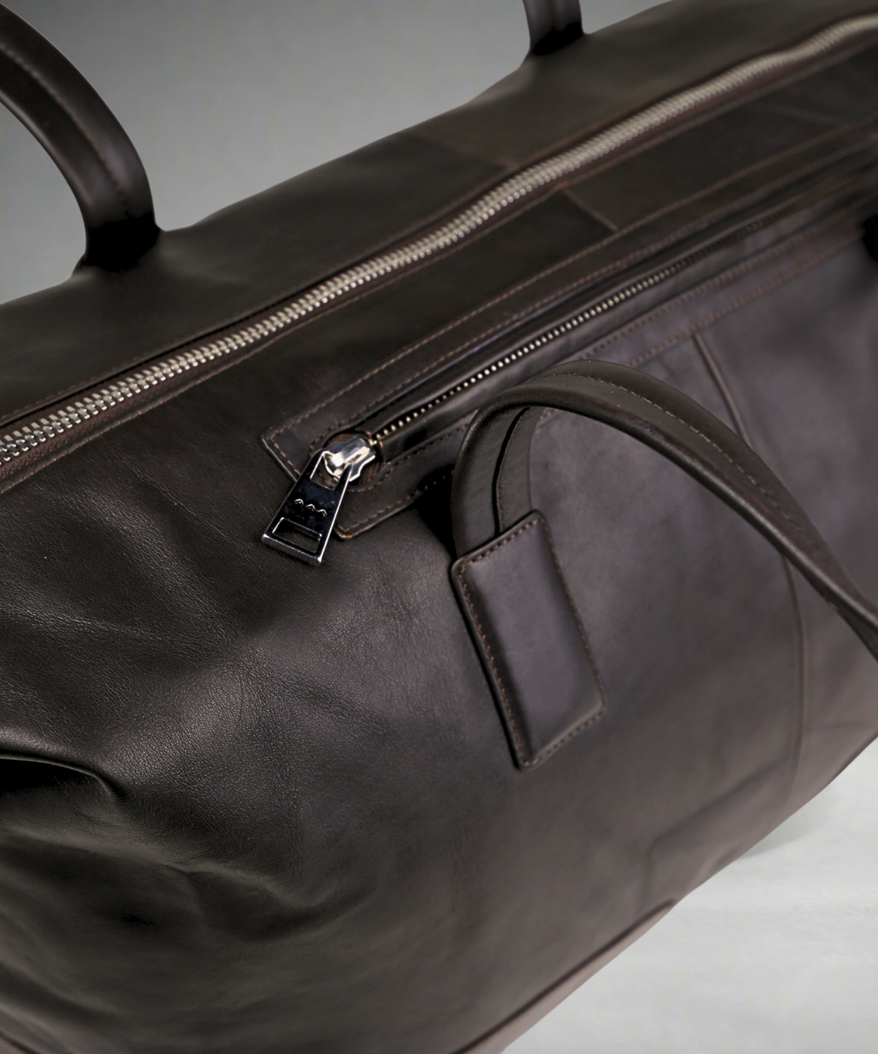Brown Royal RepubliQ leather duffel bag with zipper on a gray background