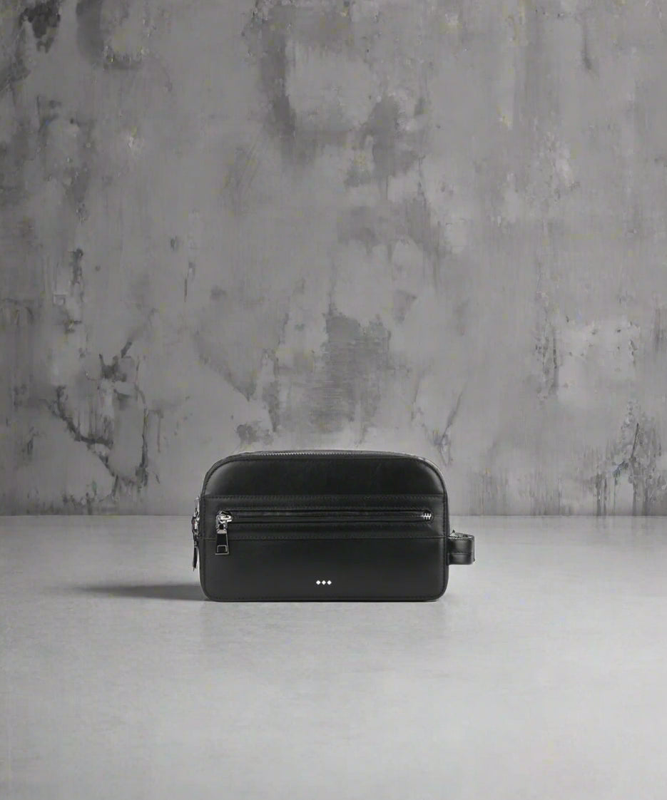 Black leather bag on a gray surface with a textured gray wall background