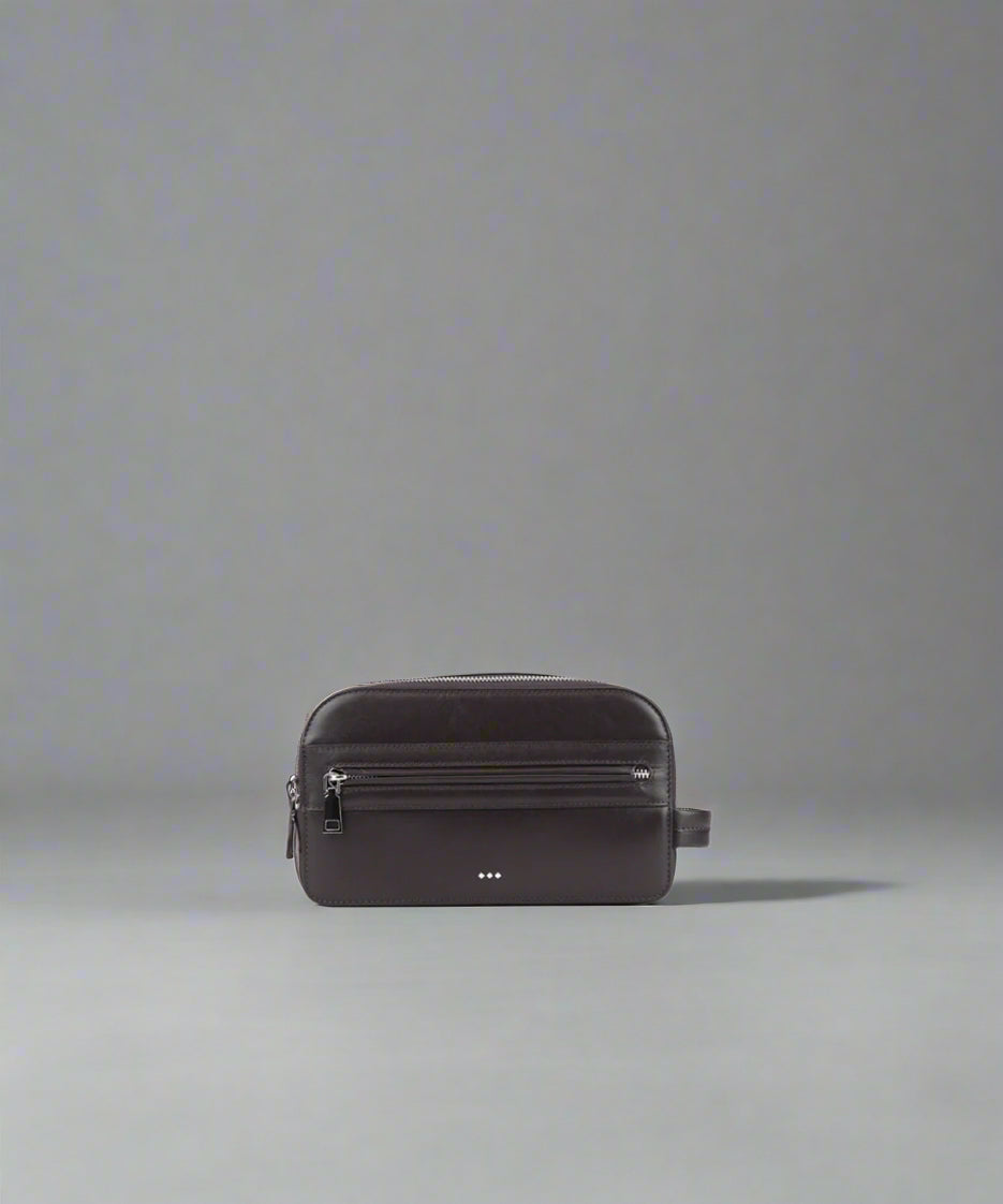 Dark brown leather bag on a gray background