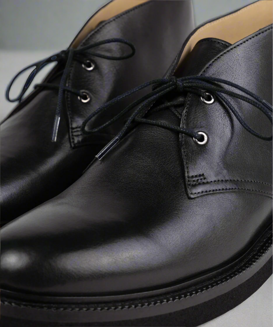 Close-up of black leather shoes with laces on a light background