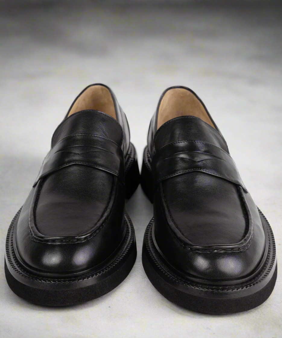 Pair of black leather loafers on a gray background