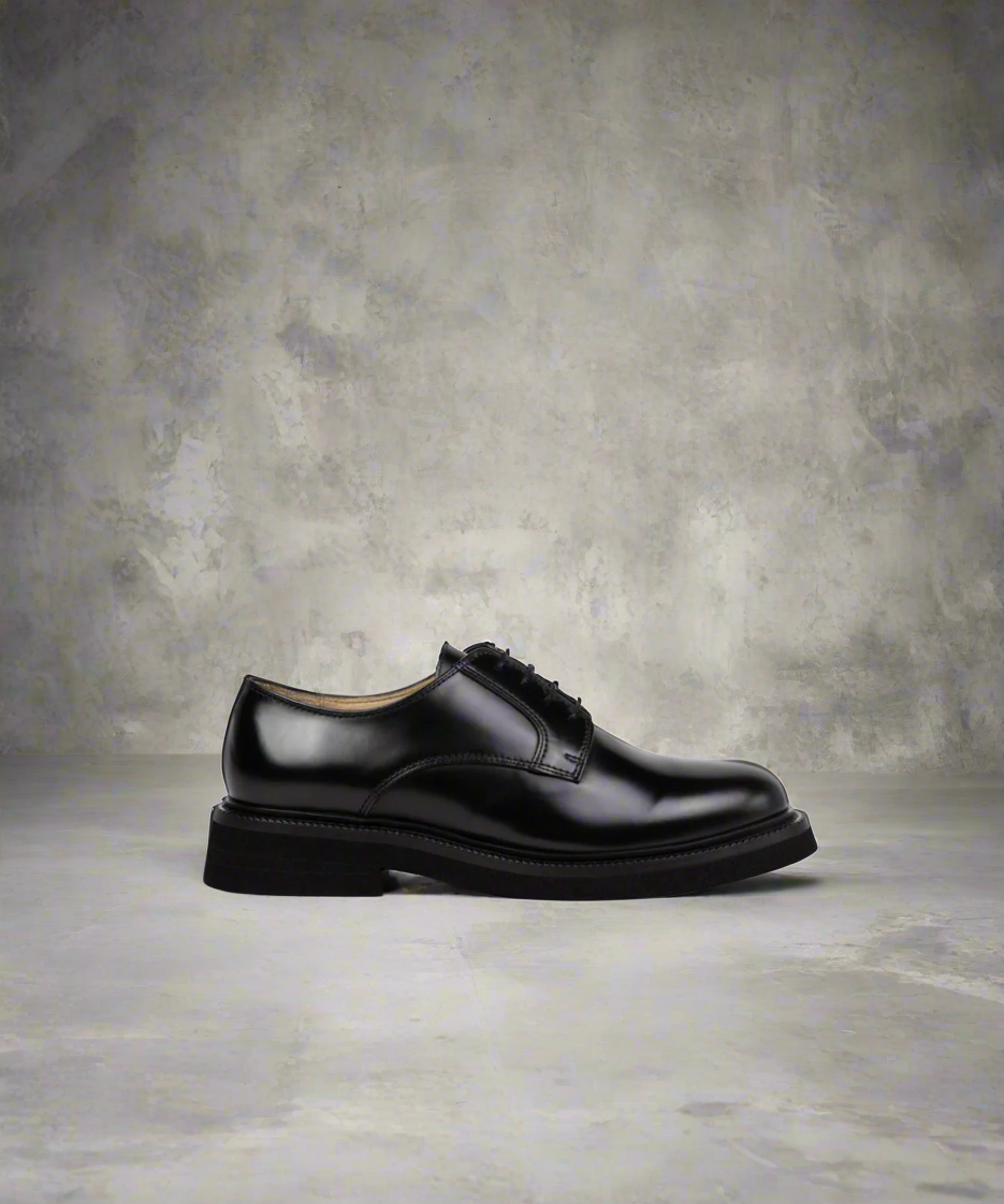 Black Royal RepubliQ leather dress shoe on a textured gray background