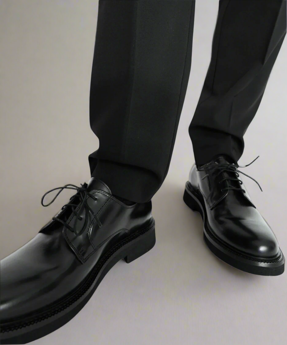 Black dress shoes and pants on a neutral background