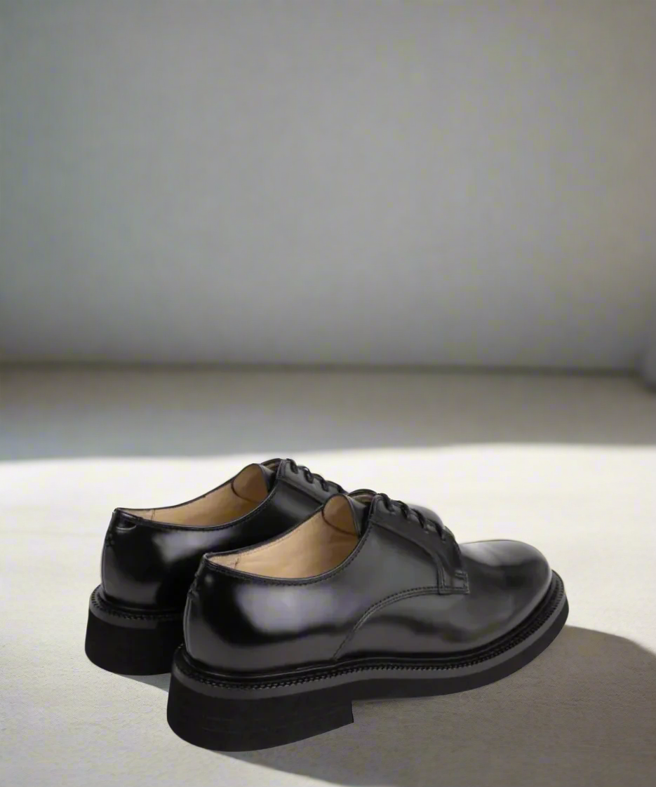 Pair of black Royal RepubliQ dress shoes on a light gray background