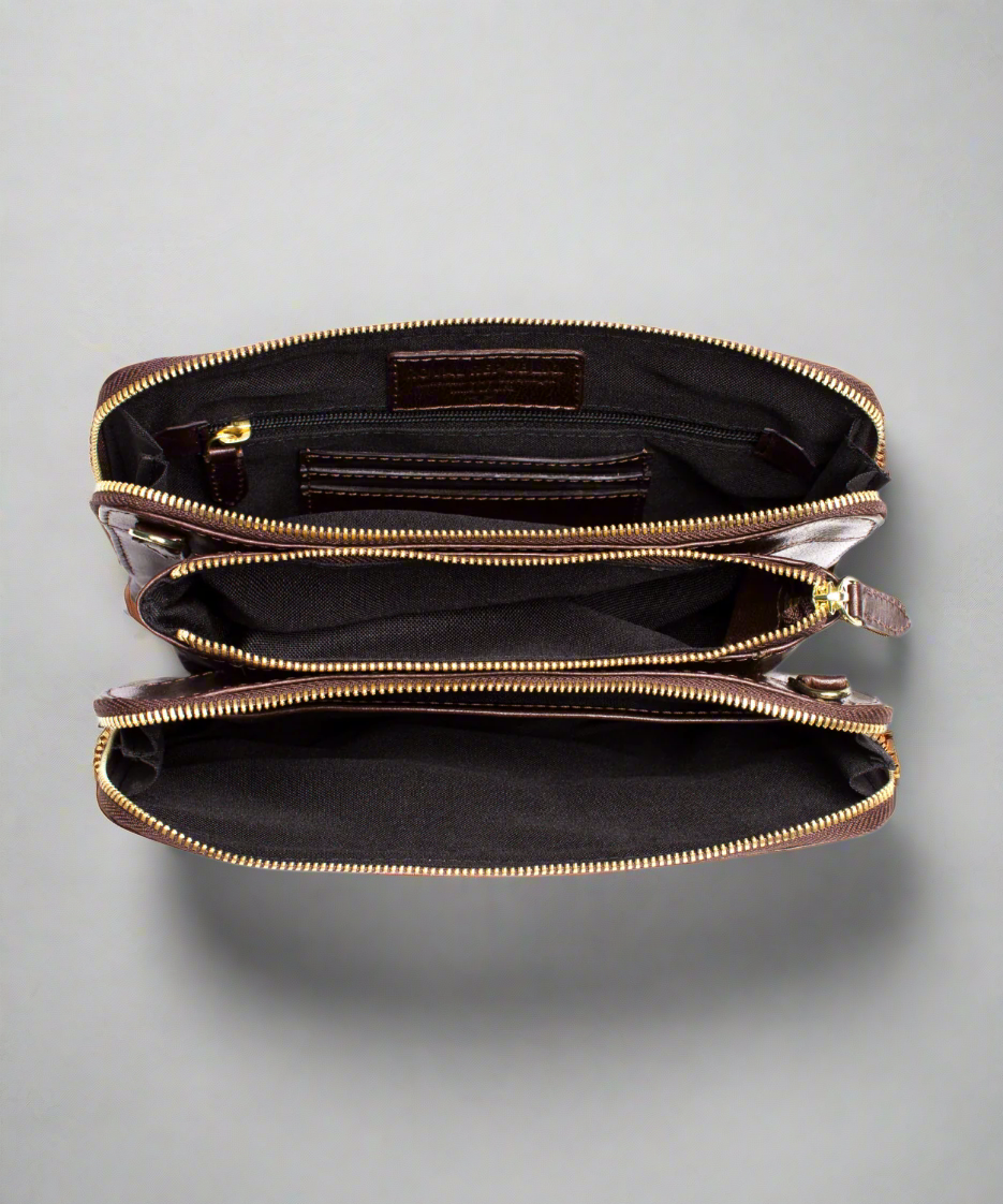Close up inside view of aBrown Royal RepubliQ leather clutch bag with a strap on a gray background
