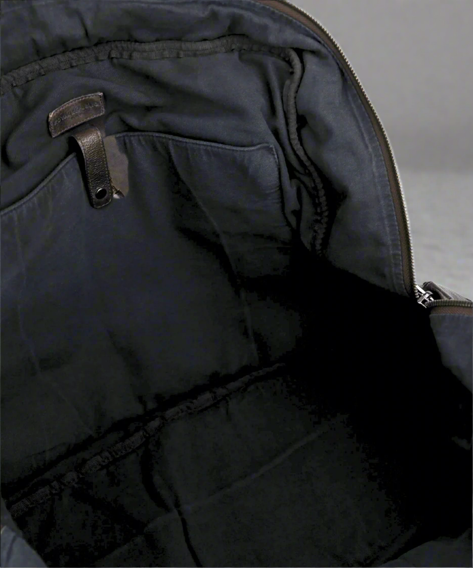 Inside close-up of a brown Royal RepubliQ washed leather weekend bag with zippers on a gray background