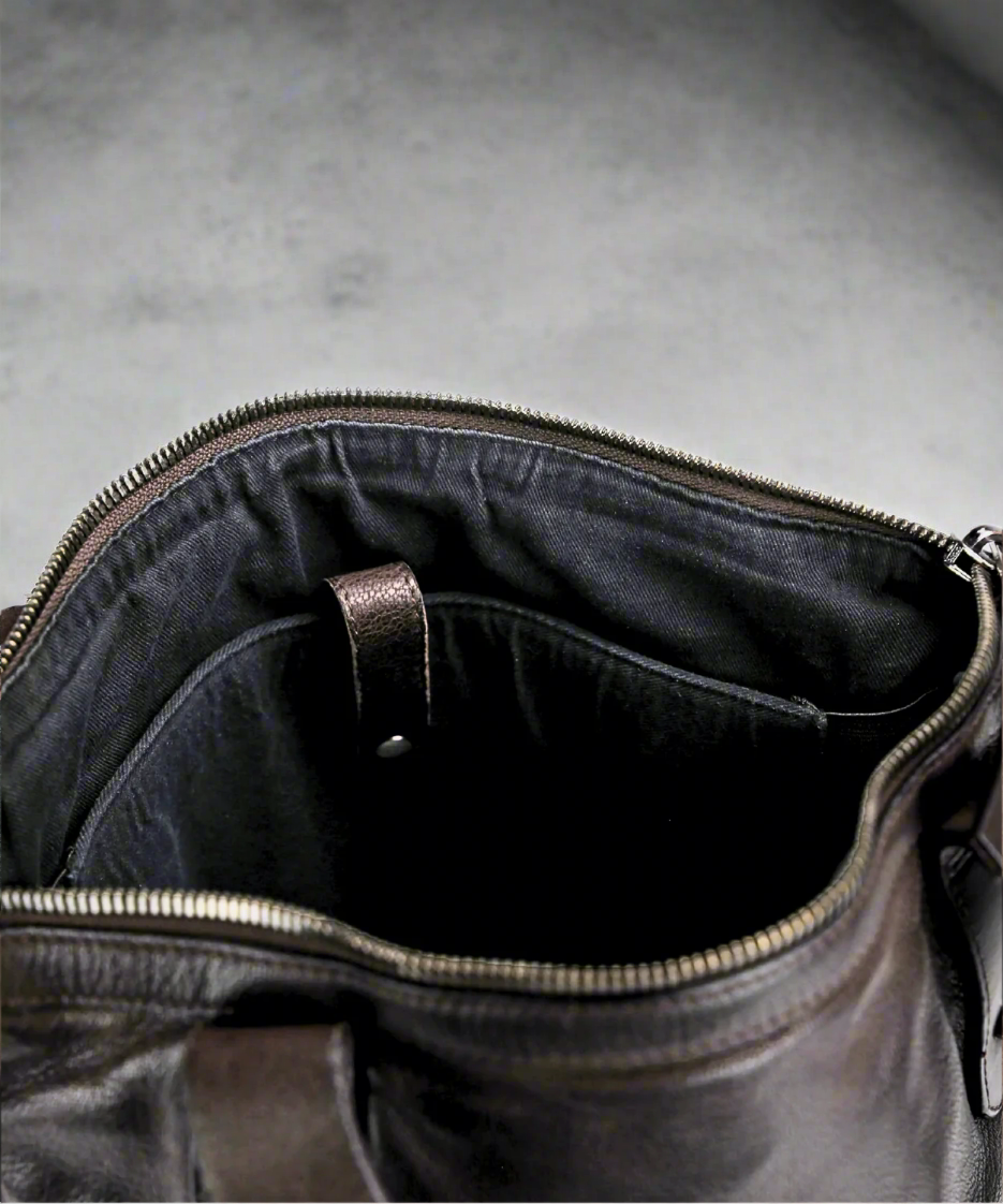 Close-up of a dark brown leather bag with a zipper, showing the interior.