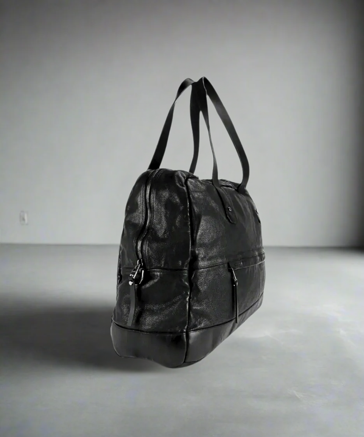 Black Royal RepubliQ washed leather weekend bag on a gray background.