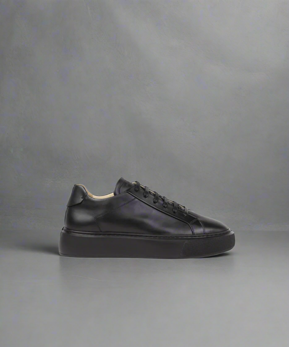 Black ROYAL REPUBLIQ leather sneaker on a gray background