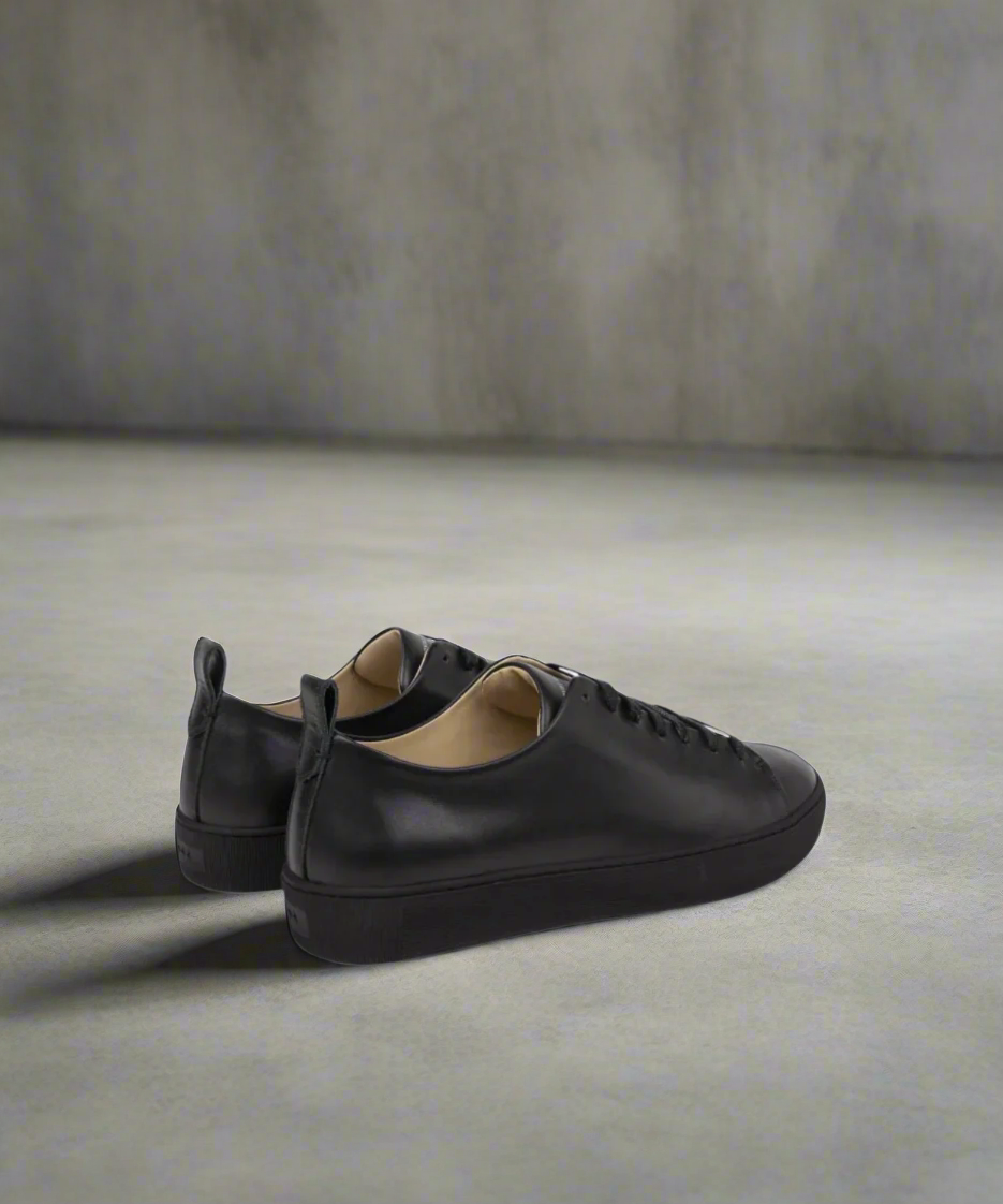 A black Royal RepubliQ leather low-top men's sneaker with lace-up closure, featuring a smooth leather upper and a flat rubber outsole, with logo emboss on outsole