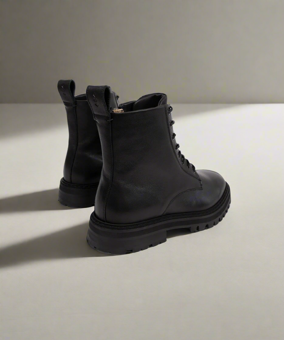 Pair of black leather boots on a light gray background