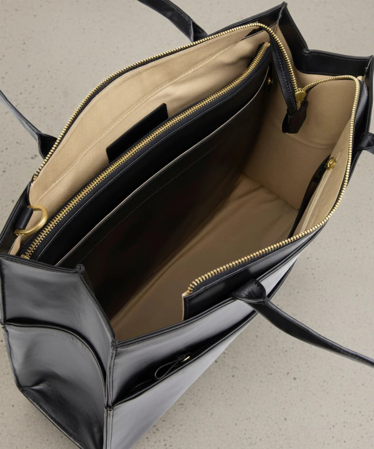 Black handbag with beige interior on a light gray background