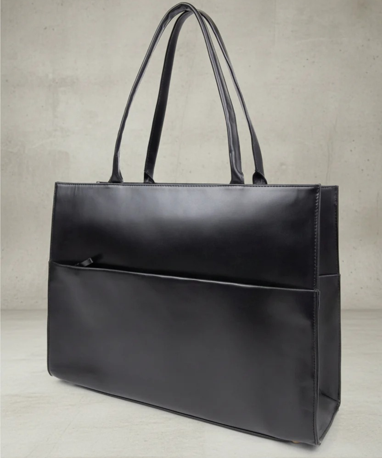 Black leather tote bag on a light gray background