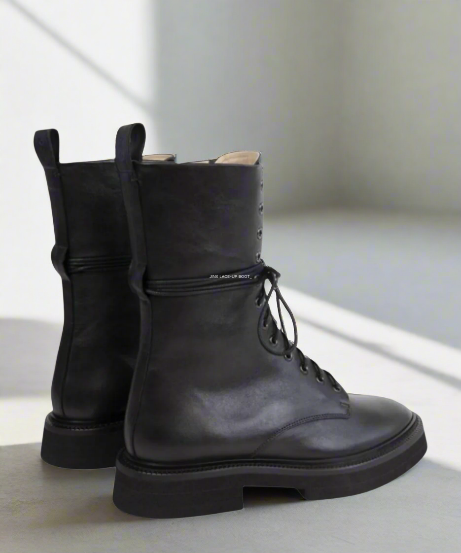 Black leather boots on a light gray surface with a white background