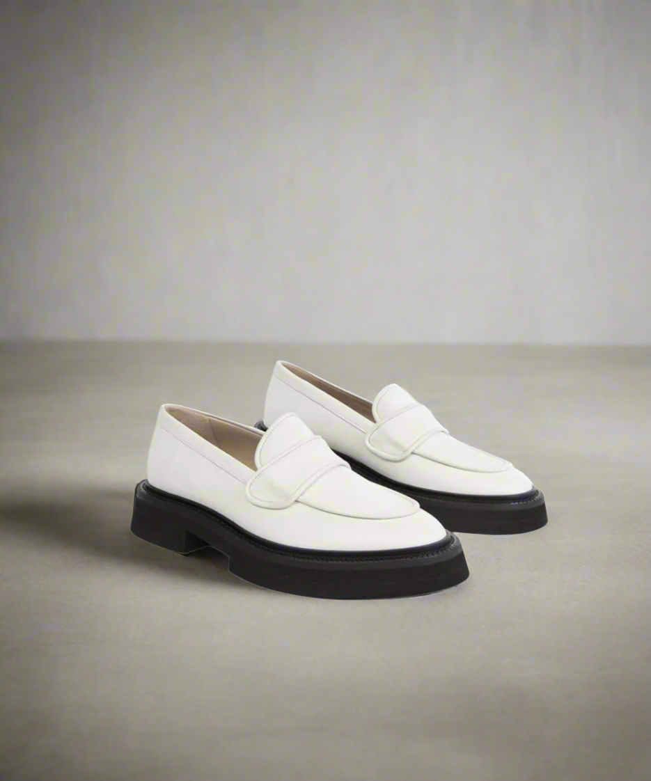 White loafers with black soles on a gray background