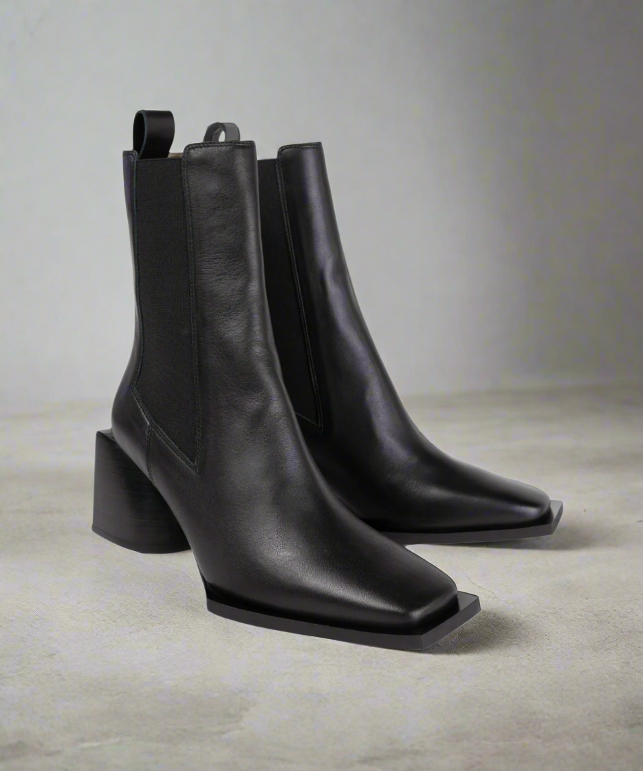 Pair of black Royal RepubliQ leather ankle Chelsea boots on a neutral background